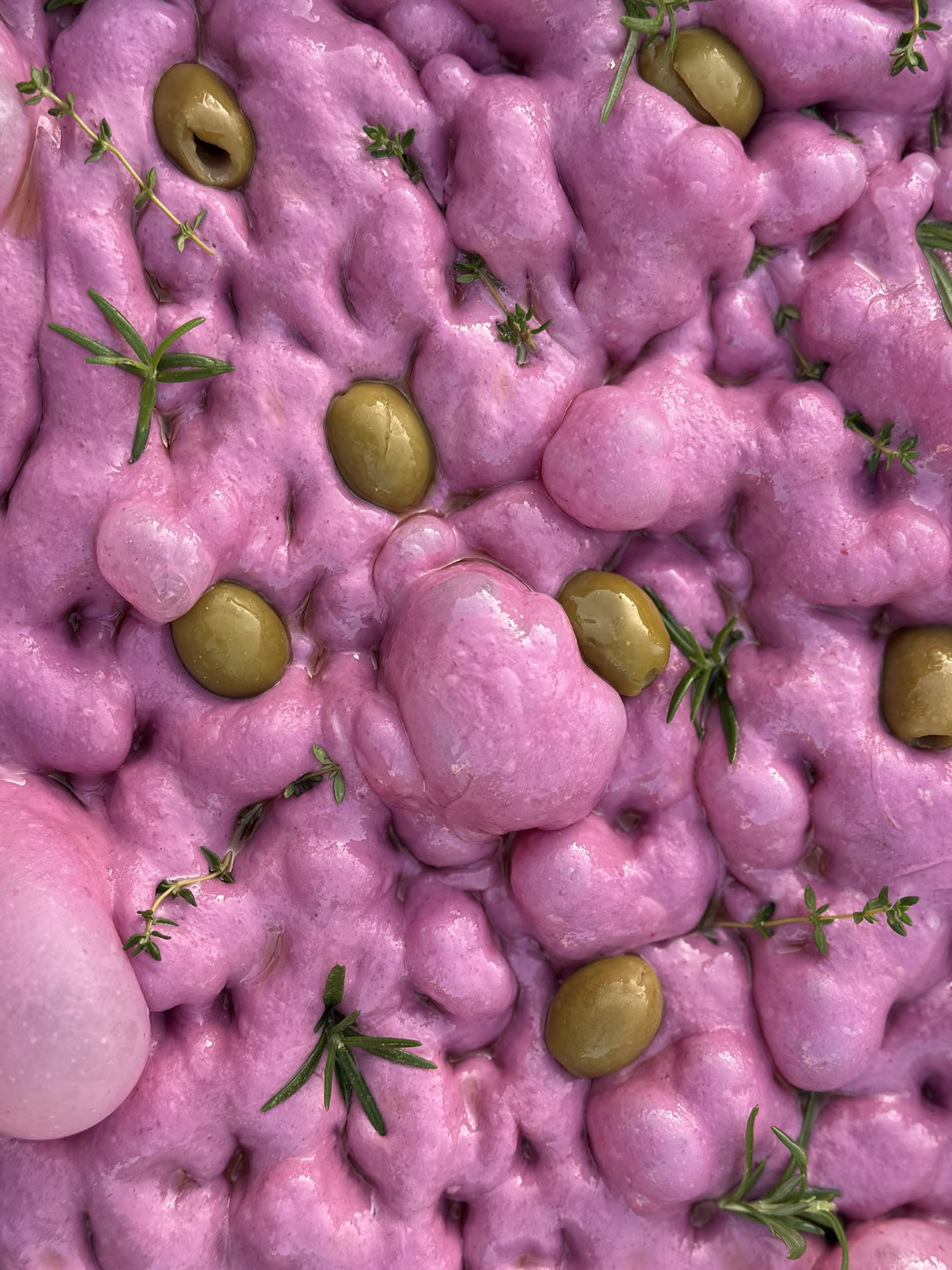 Focaccia de masa violeta con aceitunas y tomillo, vista desde arriba.