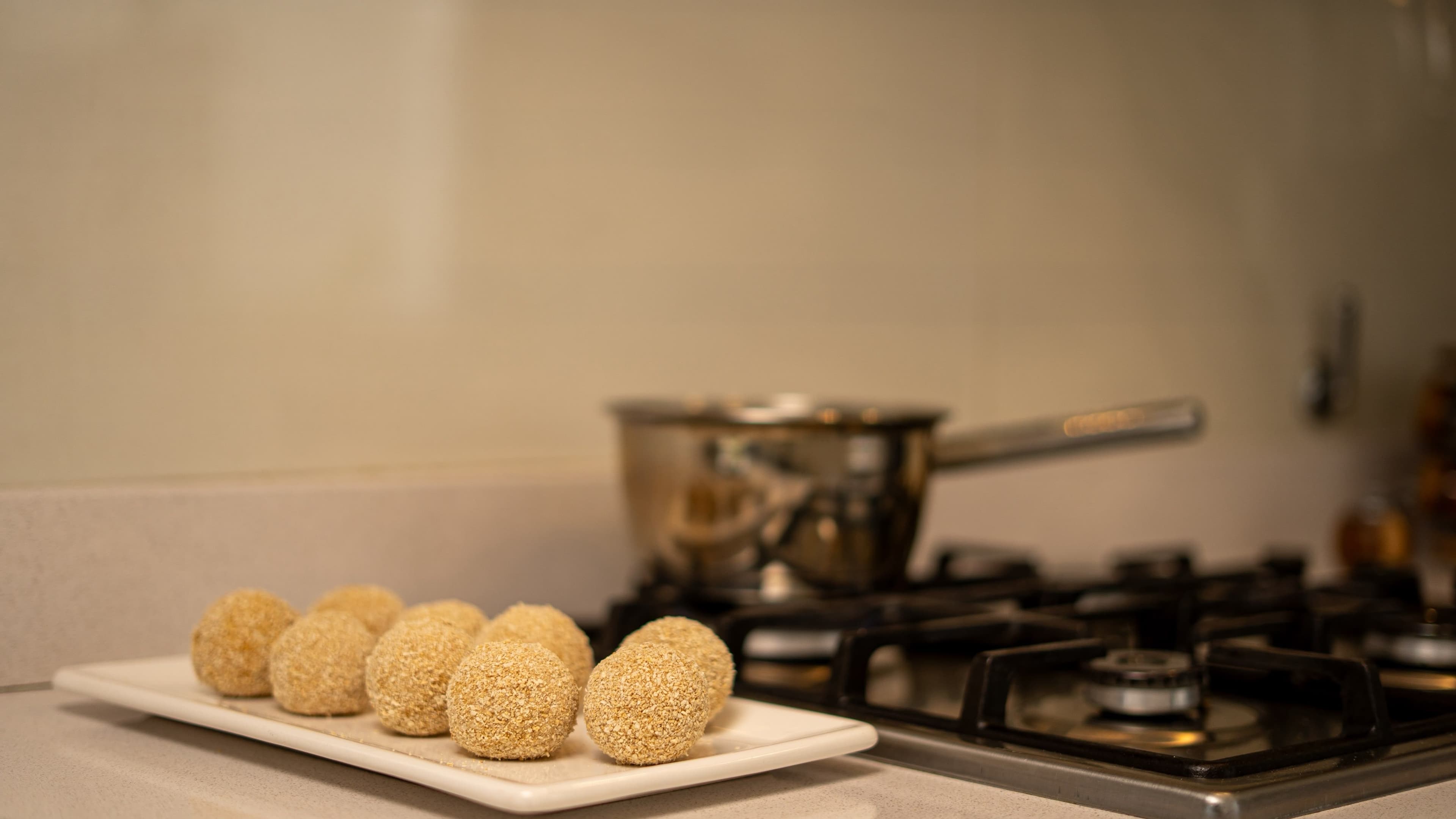 Croquetas emplatadas junto a la hornalla, en un ambiente de cocina real.