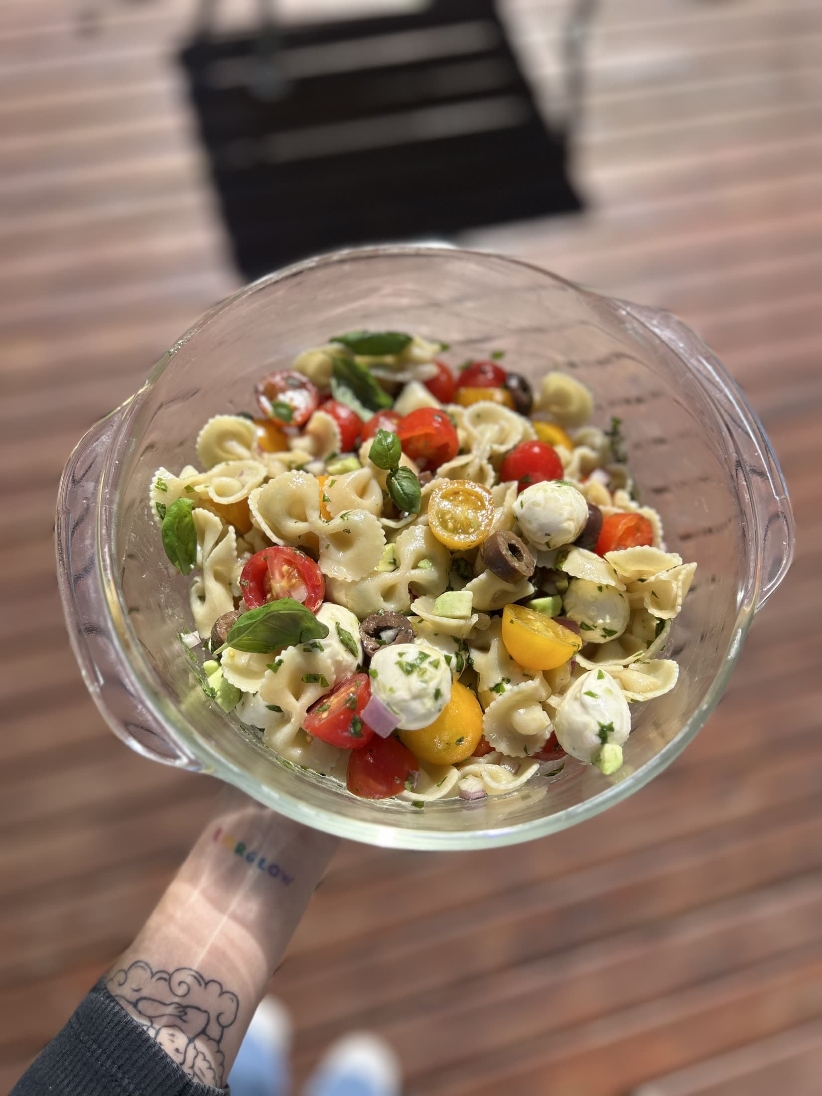 Un bowl de ensalada de pastas sostenido con las dos manos.