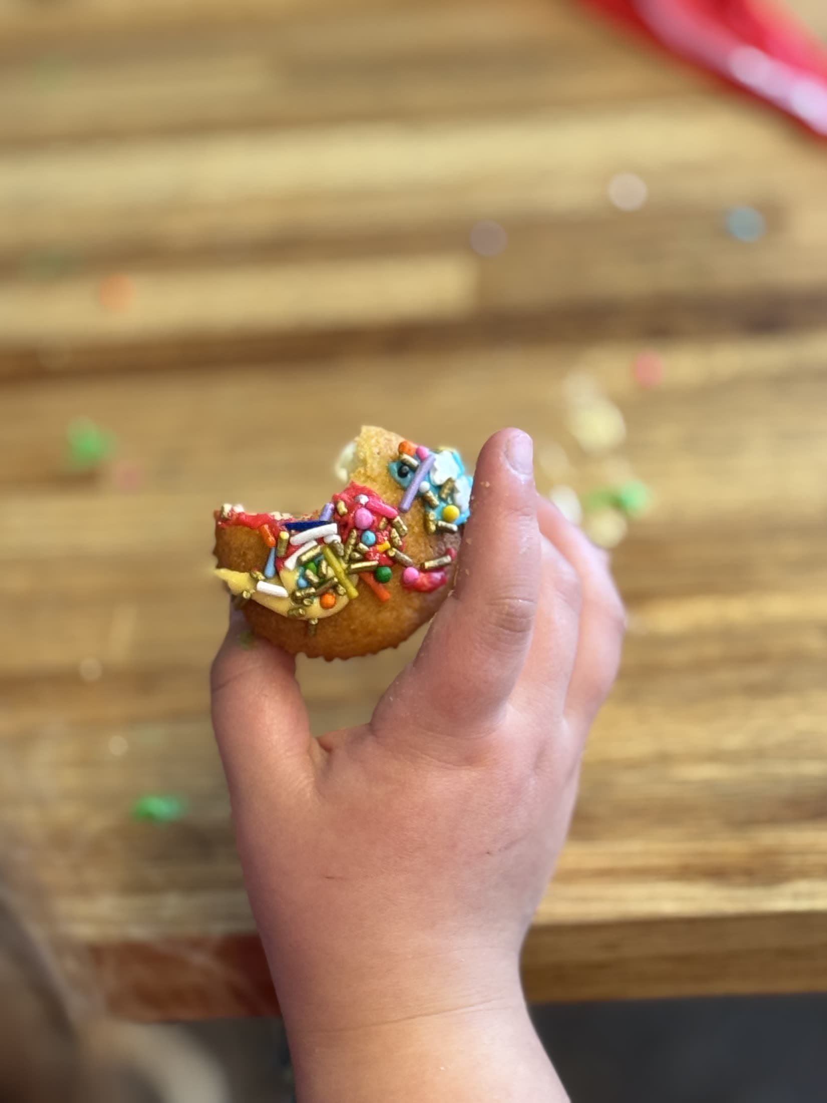 La mano de un chico levantando un cupcake decorado, con la grana cayendo.