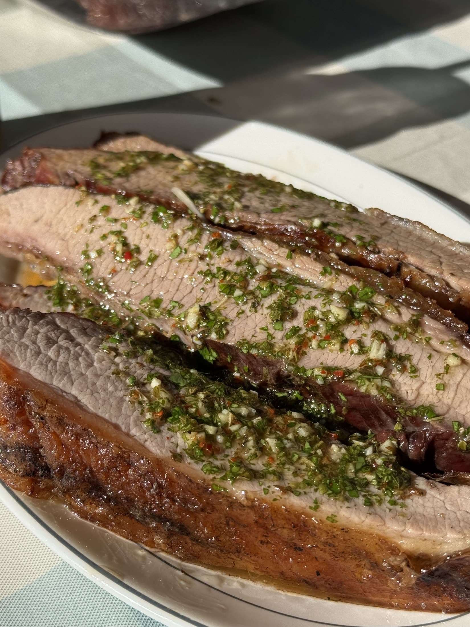 Cortes de carne asada con chimichurri encima, listos para servir.