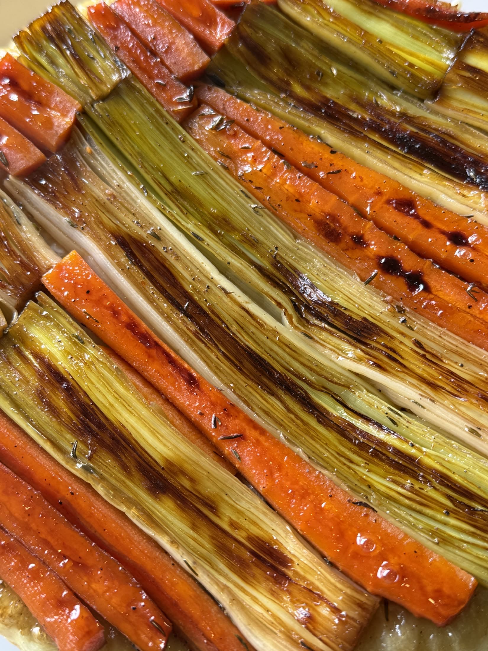 Zanahorias y puerros asados, alineados y brillantes, recién salidos del horno.