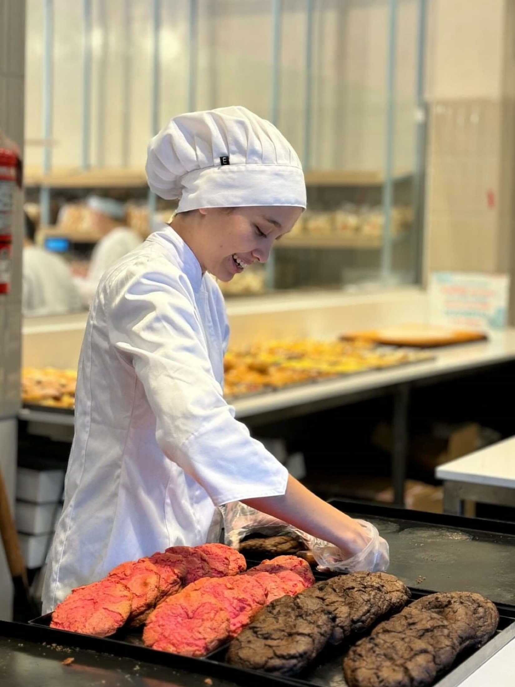 Delfina se ríe mientras acomoda una bandeja de galletones en la cocina de trabajo.